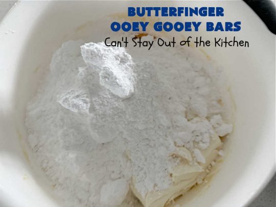 Butterfinger Ooey Gooey Bars | Can't Stay Out of the Kitchen | these lovely #OoeyGooeyBars include a #Cheesecake filling with chopped #Butterfingers on top! This easy 6-ingredient #recipe is so irresistible everyone will want seconds. They are out of this world good & will have you swooning from the first bite. Excellent for #tailgating, potlucks & a #ChristmasCookieExchange. #cookie #brownie #dessert #ButterfingerDessert #ButterfingerOoeyGooeyBars