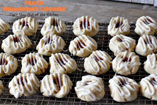 Peach Thumbprint Cookies | these fantastic little #cookies are terrific for #holiday #baking & #ChristmasCookieExchanges. They're filled with #peach jam & iced with a heavenly vanilla powdered sugar icing. #dessert #holiday #HolidayDessert ChristmasDessert #ChristmasCookie #PeachDessert #ThumbprintCookie