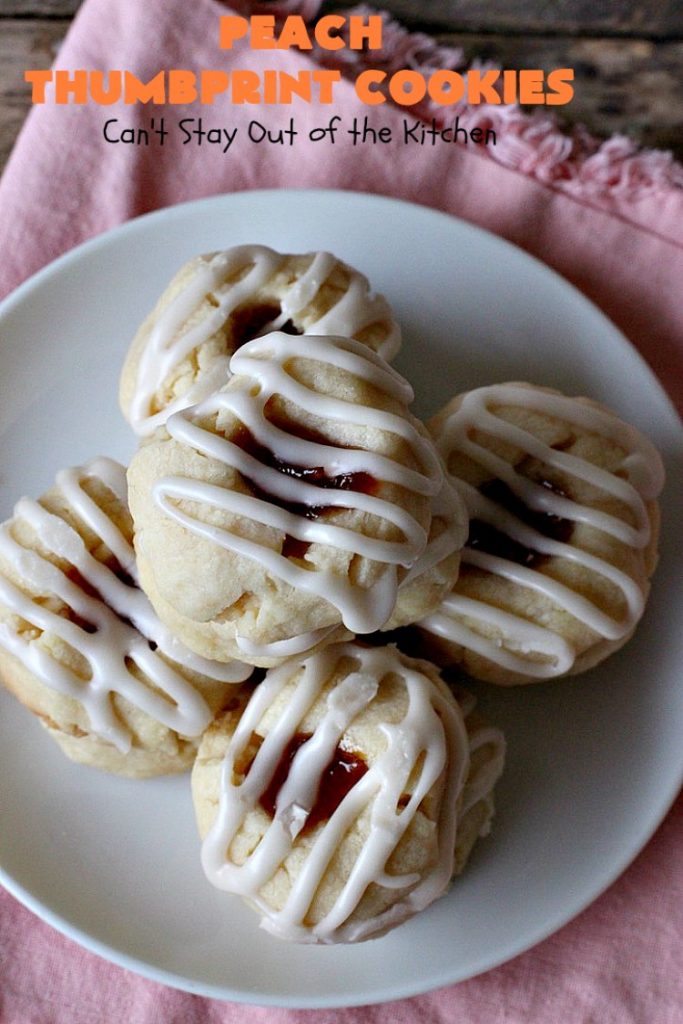 Peach Thumbprint Cookies | these fantastic little #cookies are terrific for #holiday #baking & #ChristmasCookieExchanges. They're filled with #peach jam & iced with a heavenly vanilla powdered sugar icing. #dessert #holiday #HolidayDessert ChristmasDessert #ChristmasCookie #PeachDessert #ThumbprintCookie