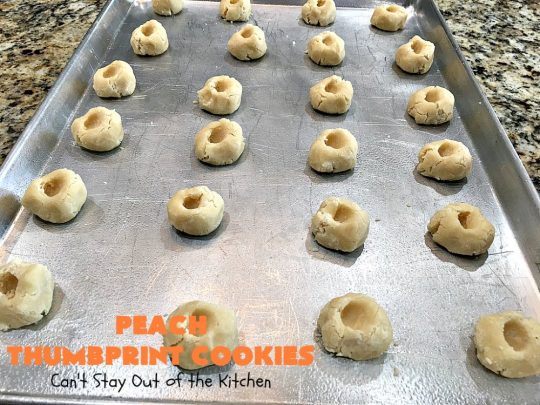 Peach Thumbprint Cookies | these fantastic little #cookies are terrific for #holiday #baking & #ChristmasCookieExchanges. They're filled with #peach jam & iced with a heavenly vanilla powdered sugar icing. #dessert #holiday #HolidayDessert ChristmasDessert #ChristmasCookie #PeachDessert #ThumbprintCookie