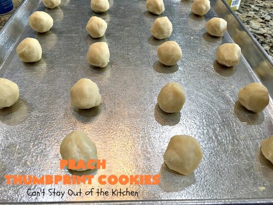 Peach Thumbprint Cookies | these fantastic little #cookies are terrific for #holiday #baking & #ChristmasCookieExchanges. They're filled with #peach jam & iced with a heavenly vanilla powdered sugar icing. #dessert #holiday #HolidayDessert ChristmasDessert #ChristmasCookie #PeachDessert #ThumbprintCookie