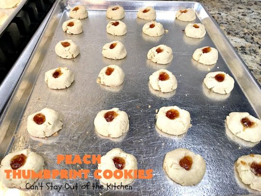 Peach Thumbprint Cookies | these fantastic little #cookies are terrific for #holiday #baking & #ChristmasCookieExchanges. They're filled with #peach jam & iced with a heavenly vanilla powdered sugar icing. #dessert #holiday #HolidayDessert ChristmasDessert #ChristmasCookie #PeachDessert #ThumbprintCookie