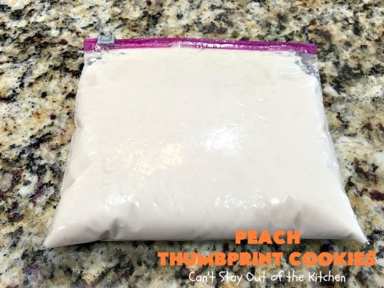 Peach Thumbprint Cookies | these fantastic little #cookies are terrific for #holiday #baking & #ChristmasCookieExchanges. They're filled with #peach jam & iced with a heavenly vanilla powdered sugar icing. #dessert #holiday #HolidayDessert ChristmasDessert #ChristmasCookie #PeachDessert #ThumbprintCookie