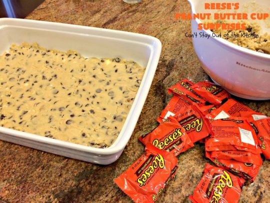 Reese's Peanut Butter Cup Surprises | Can't Stay Out of the Kitchen | these awesome #brownies have #ReesesPeanutButterCups tucked away between two layers of #MrsFieldsChocolateChipCookie dough. They are rich, decadent & absolutely heavenly. Perfect for #tailgating parties, a company #dessert or a #ChristmasCookieExchange. #PeanutButter #PeanutButterCups #chocolate #ReesesPeanutButterCupSurprises