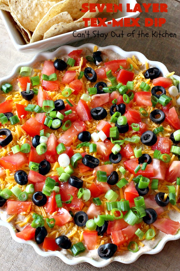 Seven Layer Tex-Mex Dip | Can't Stay Out of the Kitchen | this awesome #TexMex #dip is out of this world. It's terrific for any kind of company or #holiday party. We like it for #tailgating parties & potlucks. Also great for summer #holidays like #FourthOfJuly. #GlutenFree #Mexican #TexMexDip #LayeredMexicanDip #RefriedBeans #Jalapenos #Olives #CheddarCheese #Guacamole #TortillaChips #tomatoes #Avocados #SevenLayerTexMexDip #appetizer #TexMexAppetizer