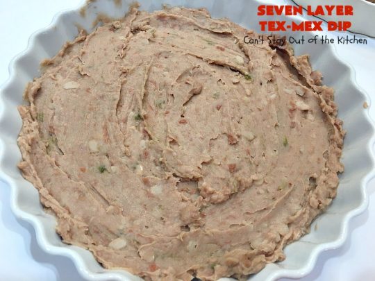 Seven Layer Tex-Mex Dip | Can't Stay Out of the Kitchen | this awesome #TexMex #dip is out of this world. It's terrific for any kind of company or #holiday party. We like it for #tailgating parties & potlucks. Also great for summer #holidays like #FourthOfJuly. #GlutenFree #Mexican #TexMexDip #LayeredMexicanDip #RefriedBeans #Jalapenos #Olives #CheddarCheese #Guacamole #TortillaChips #tomatoes #Avocados #SevenLayerTexMexDip #appetizer #TexMexAppetizer