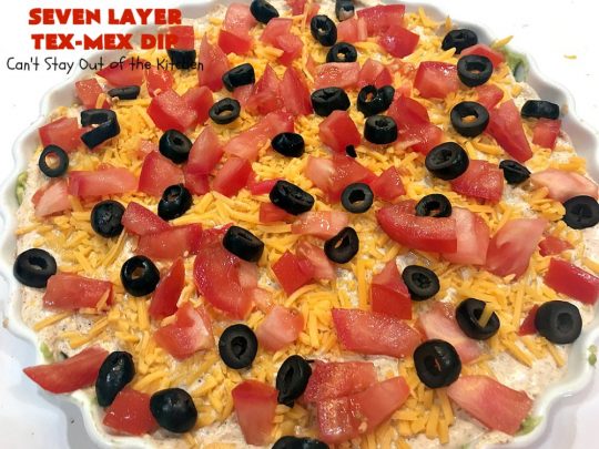 Seven Layer Tex-Mex Dip | Can't Stay Out of the Kitchen | this awesome #TexMex #dip is out of this world. It's terrific for any kind of company or #holiday party. We like it for #tailgating parties & potlucks. Also great for summer #holidays like #FourthOfJuly. #GlutenFree #Mexican #TexMexDip #LayeredMexicanDip #RefriedBeans #Jalapenos #Olives #CheddarCheese #Guacamole #TortillaChips #tomatoes #Avocados #SevenLayerTexMexDip #appetizer #TexMexAppetizer
