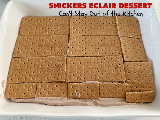 Snickers Éclair Dessert | Can't Stay Out of the Kitchen | this easy-peasy 6-ingredient #recipe is spectacular for company, potlucks or special occasions like #ValentinesDay. It includes layers of #ChocolatePudding, #GrahamCrackers, #ChocolateIcing and #SnickersCandyBars on top. The #Snickers give it that wonderful chocolaty & #caramel flavor along with #peanuts that adds a little punch to the #dessert. So easy even a child can make it! #Éclairs #ÉclairDessert #SnickersÉclairDessert