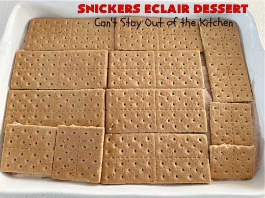 Snickers Éclair Dessert | Can't Stay Out of the Kitchen | this easy-peasy 6-ingredient #recipe is spectacular for company, potlucks or special occasions like #ValentinesDay. It includes layers of #ChocolatePudding, #GrahamCrackers, #ChocolateIcing and #SnickersCandyBars on top. The #Snickers give it that wonderful chocolaty & #caramel flavor along with #peanuts that adds a little punch to the #dessert. So easy even a child can make it! #Éclairs #ÉclairDessert #SnickersÉclairDessert