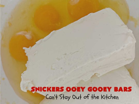 Snickers Ooey Gooey Bars | Can't Stay Out of the Kitchen | these luscious #OoeyGooeyBars contain a #cheesecake layer & they're topped with #SnickersBars for a lovely #chocolate & #PeanutButter flavor that will win over all your family & friends. This 6-ingredient #recipe is perfect for #tailgating parties, potlucks or a #ChristmasCookieExchange. It's easy to whip up & everyone loves them! #holiday #HolidayDessert #SnickersDessert #dessert #brownie #SnickersOoeyGooeyBars
