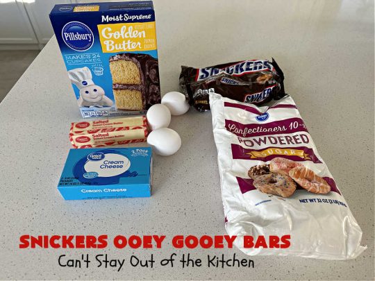 Snickers Ooey Gooey Bars | Can't Stay Out of the Kitchen | these luscious #OoeyGooeyBars contain a #cheesecake layer & they're topped with #SnickersBars for a lovely #chocolate & #PeanutButter flavor that will win over all your family & friends. This 6-ingredient #recipe is perfect for #tailgating parties, potlucks or a #ChristmasCookieExchange. It's easy to whip up & everyone loves them! #holiday #HolidayDessert #SnickersDessert #dessert #brownie #SnickersOoeyGooeyBars
