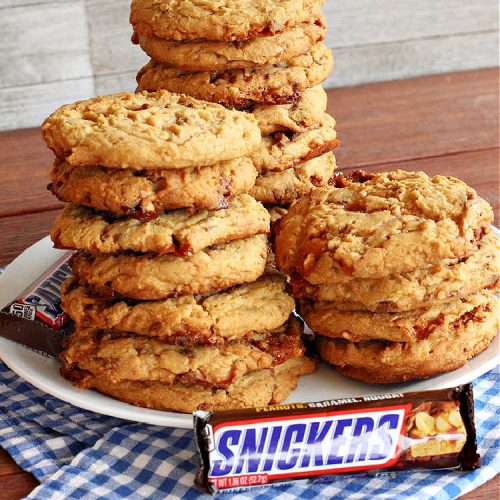 Snickers Surprises | Can't Stay Out of the Kitchen | these scrumptious #PeanutButterCookies include #SnickersBars so they have a little bit of #caramel, #chocolate & #PeanutButter in every bite. You're sure to swoon once you get a taste of these jewels. Perfect for #tailgating, potlucks, backyard BBQs and #holiday #baking. #ChristmasCookieExchange #dessert #ChocolateDessert #SnickersDessert #PeanutButterDessert #CaramelDessert #cookies #SnickersSurprises